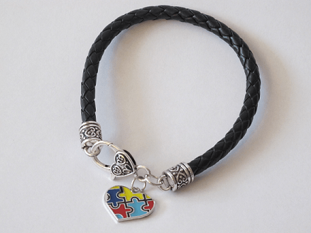 Embrace Difference- Awareness Bracelet - Tumble into Love.  Black braided bracelet with silver and black ends.  One enamel heart charm with colorful puzzle peices (blue, yellow, red)